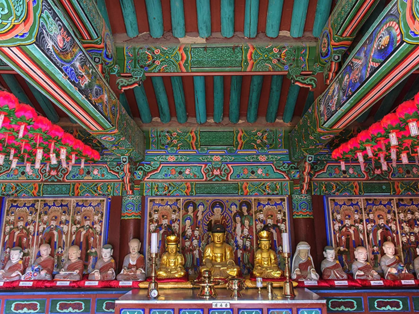 Buddha statues sitting in a brightly colored temple.