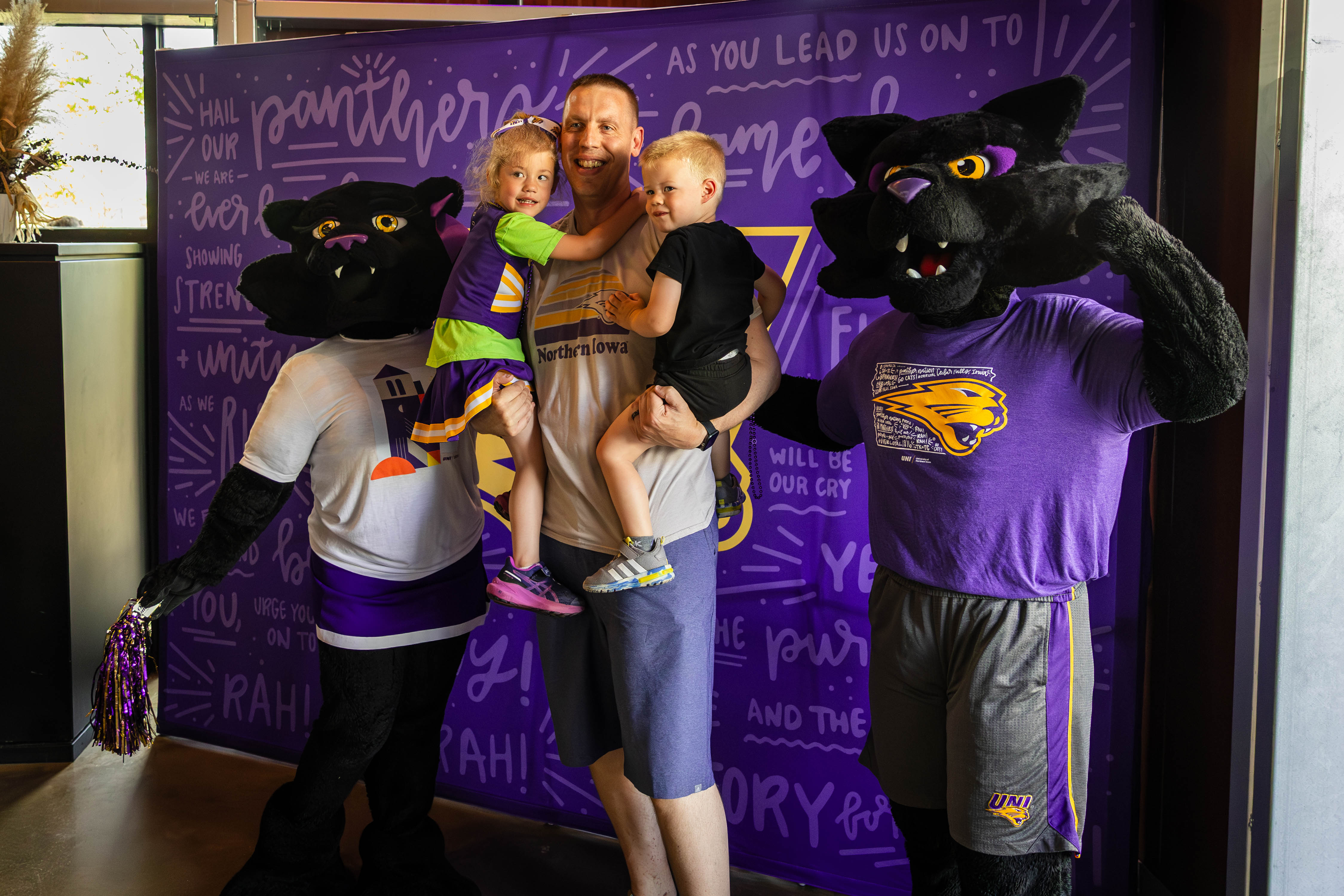 UNI alum holding his two kids next to TC and TK.