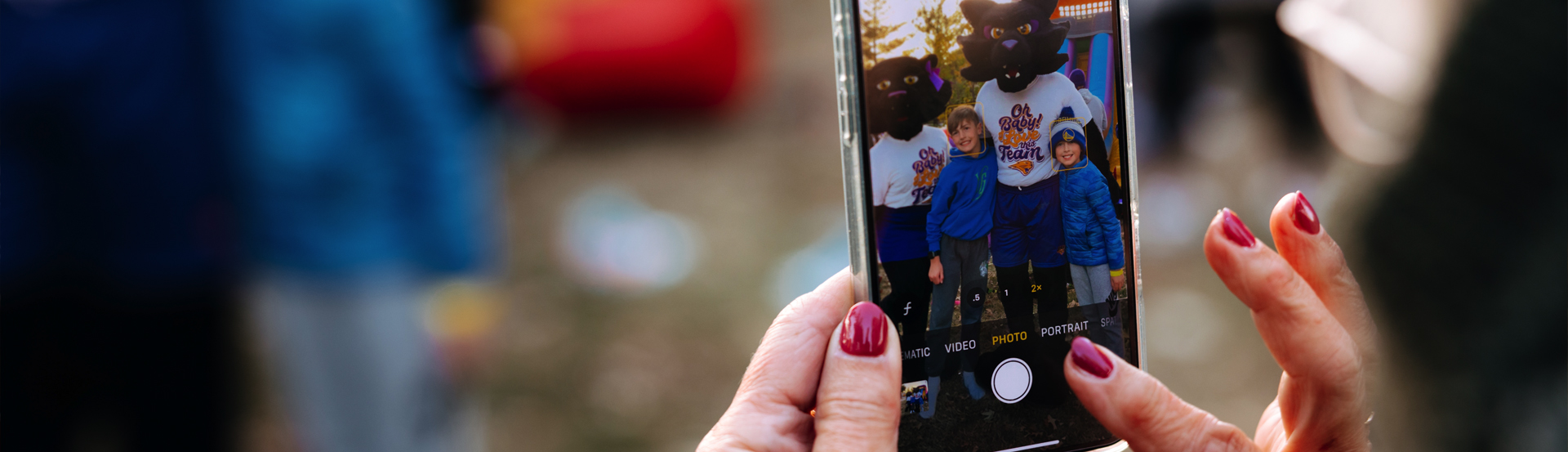Someone capturing a photo of TK & TC Panther with kids at a UNI event