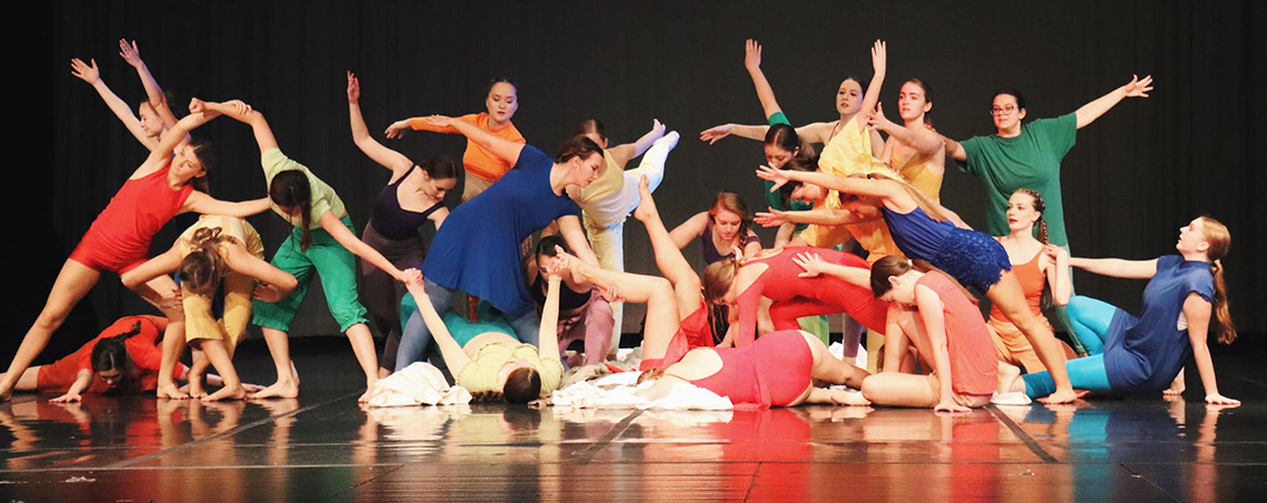 Orchesis performance with many students in brightly colored outfits