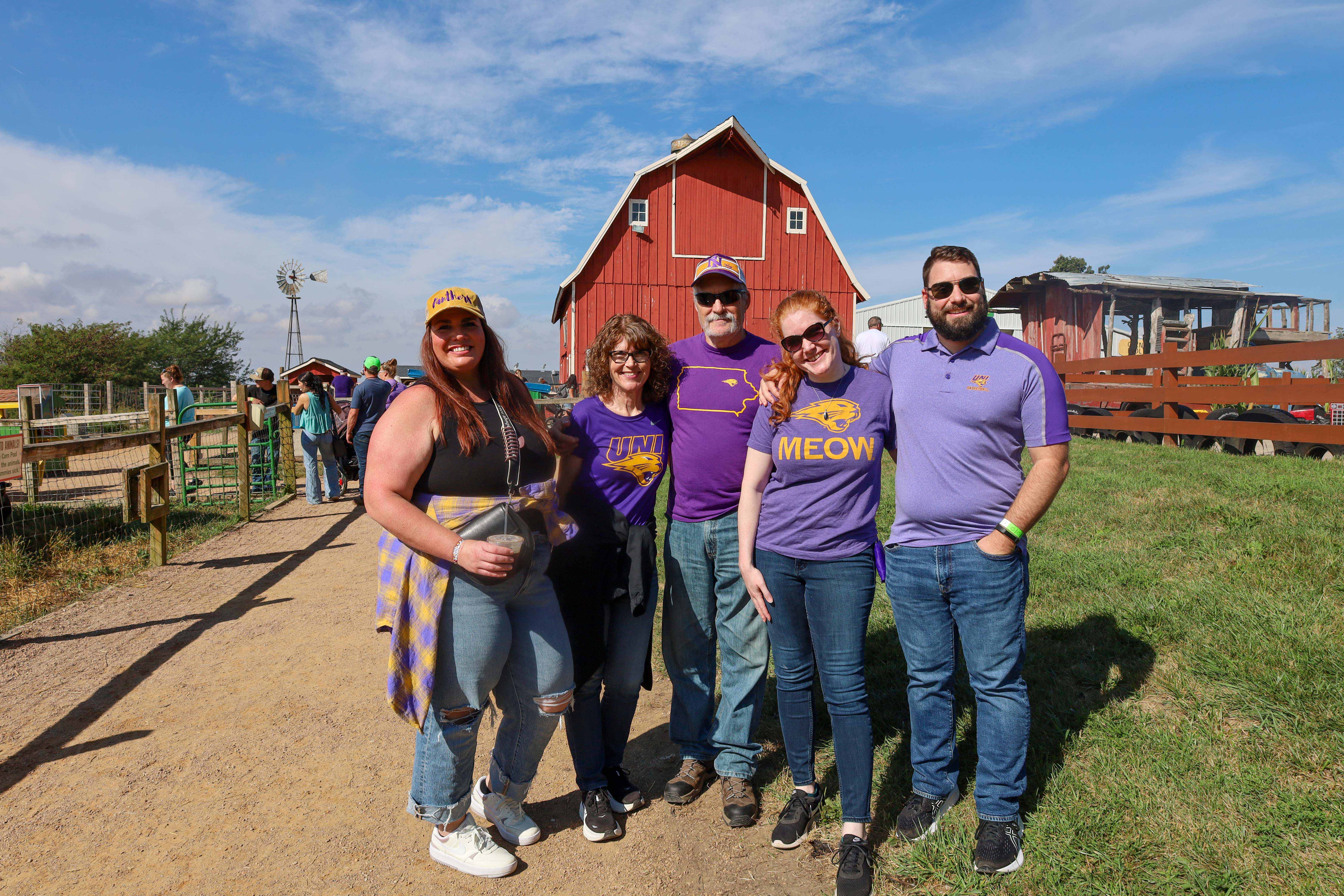 Group of UNI alumni smiling at the camera in front of a barn.