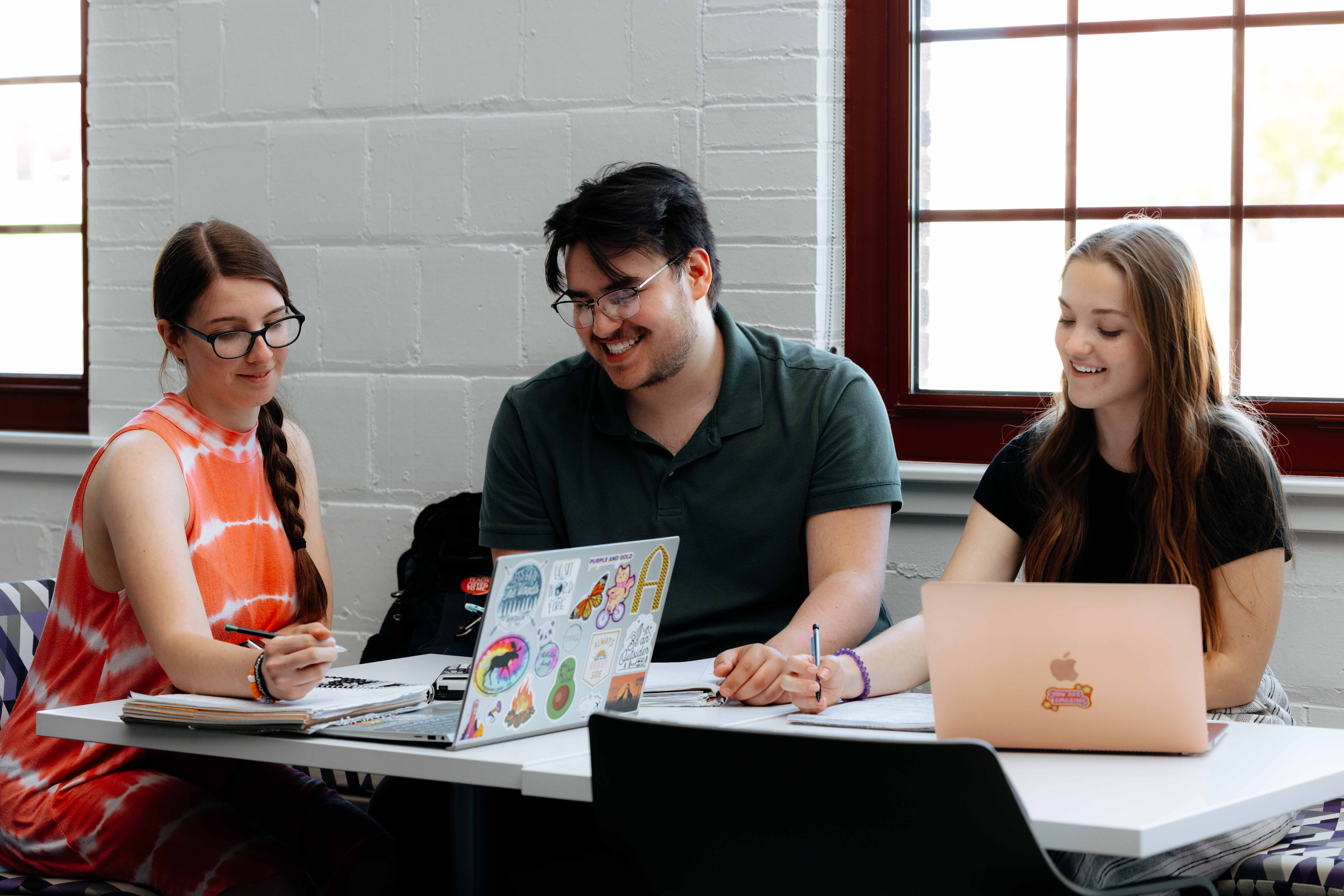 Three friends with computers sitting at a table.