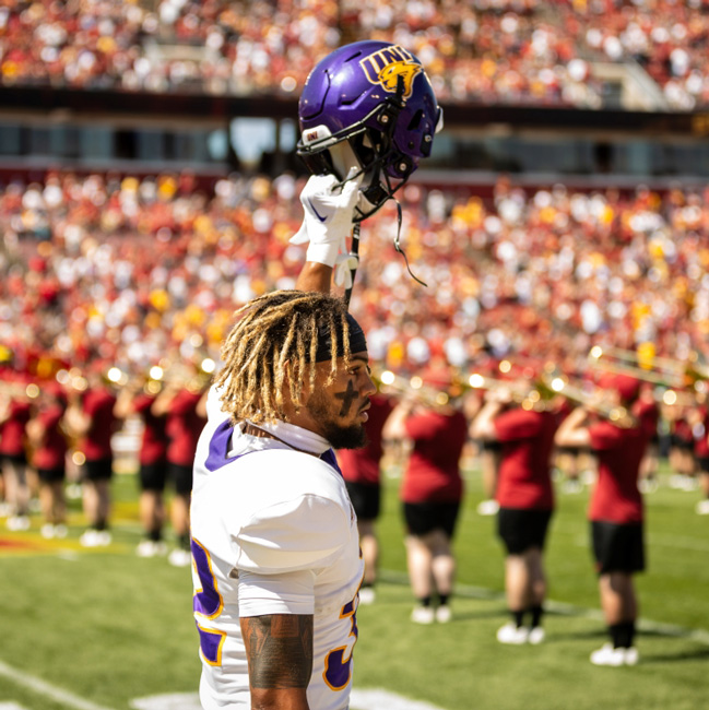 UNI football player with his helmet raised in the air during a game