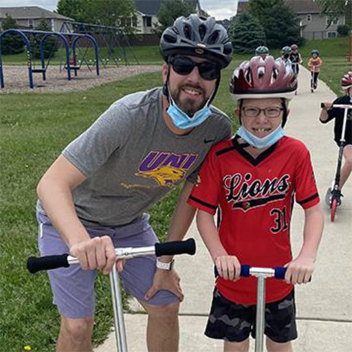 Tanner Roos with student in bike helmets on scooters