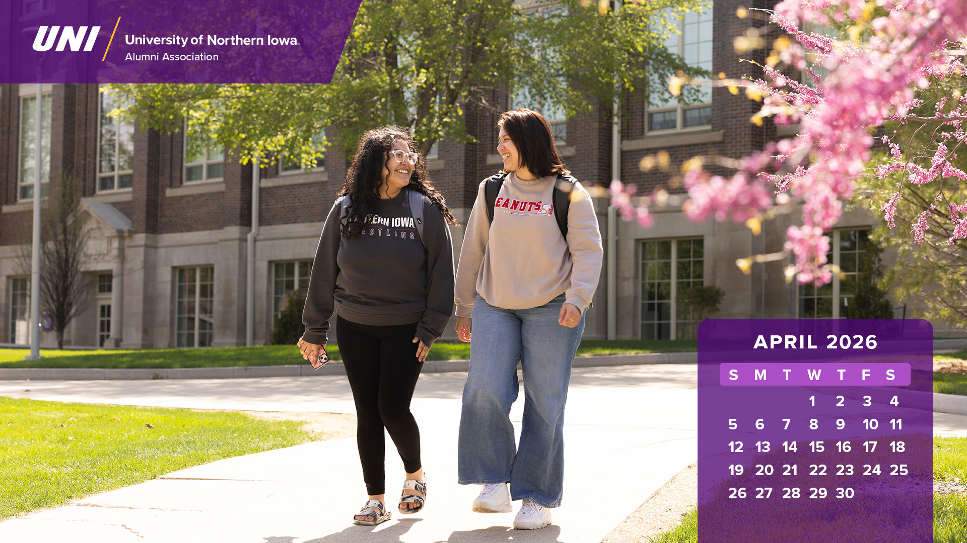 Two UNI students walking on campus during spring with calendar graphics.