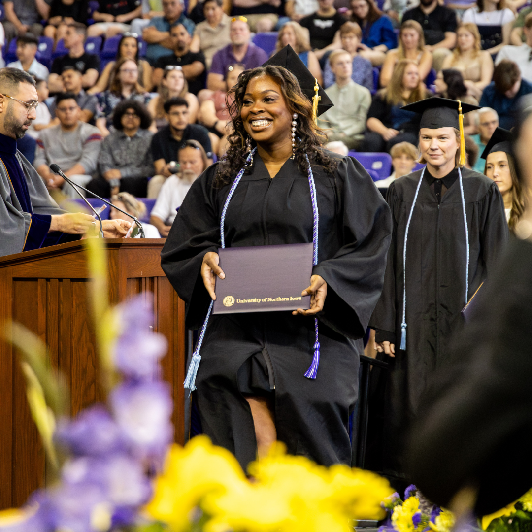 Student walking across stage at Commencement.