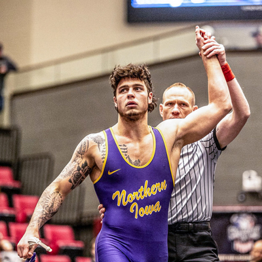 UNI student-athlete wrestler with his hand raised in the air after a win on the mat